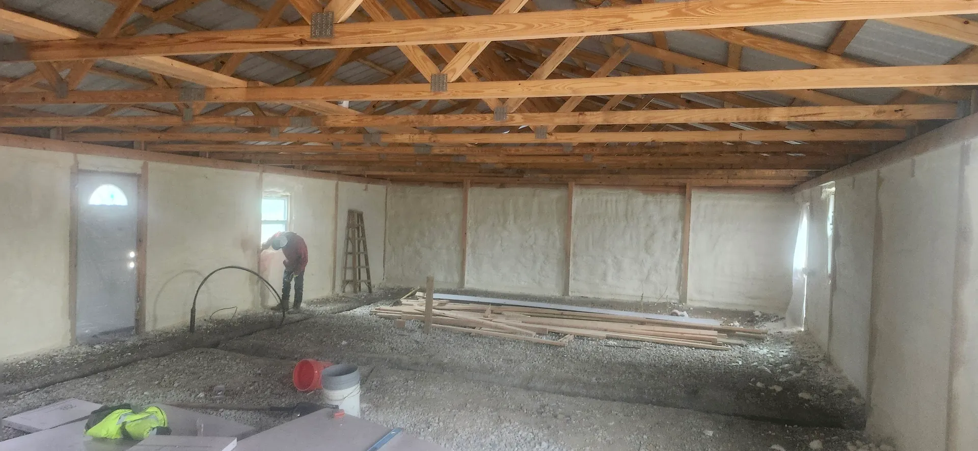 Worker spraying foam on walls in large room