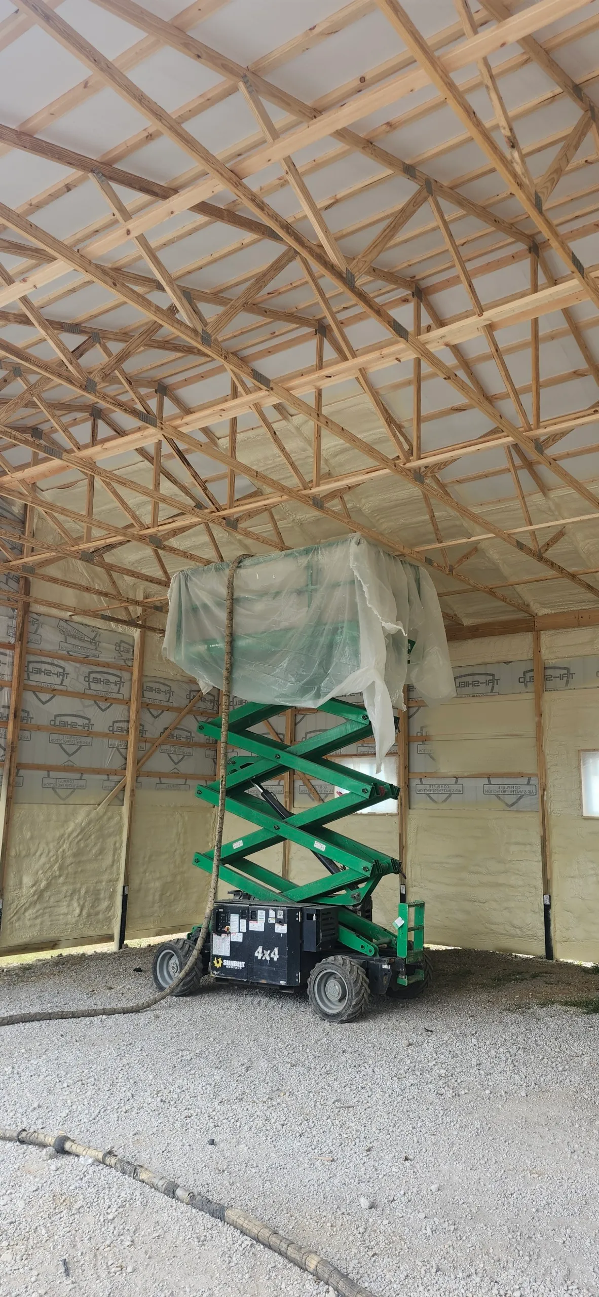 Scissor lift inside pole barn during spray foam application