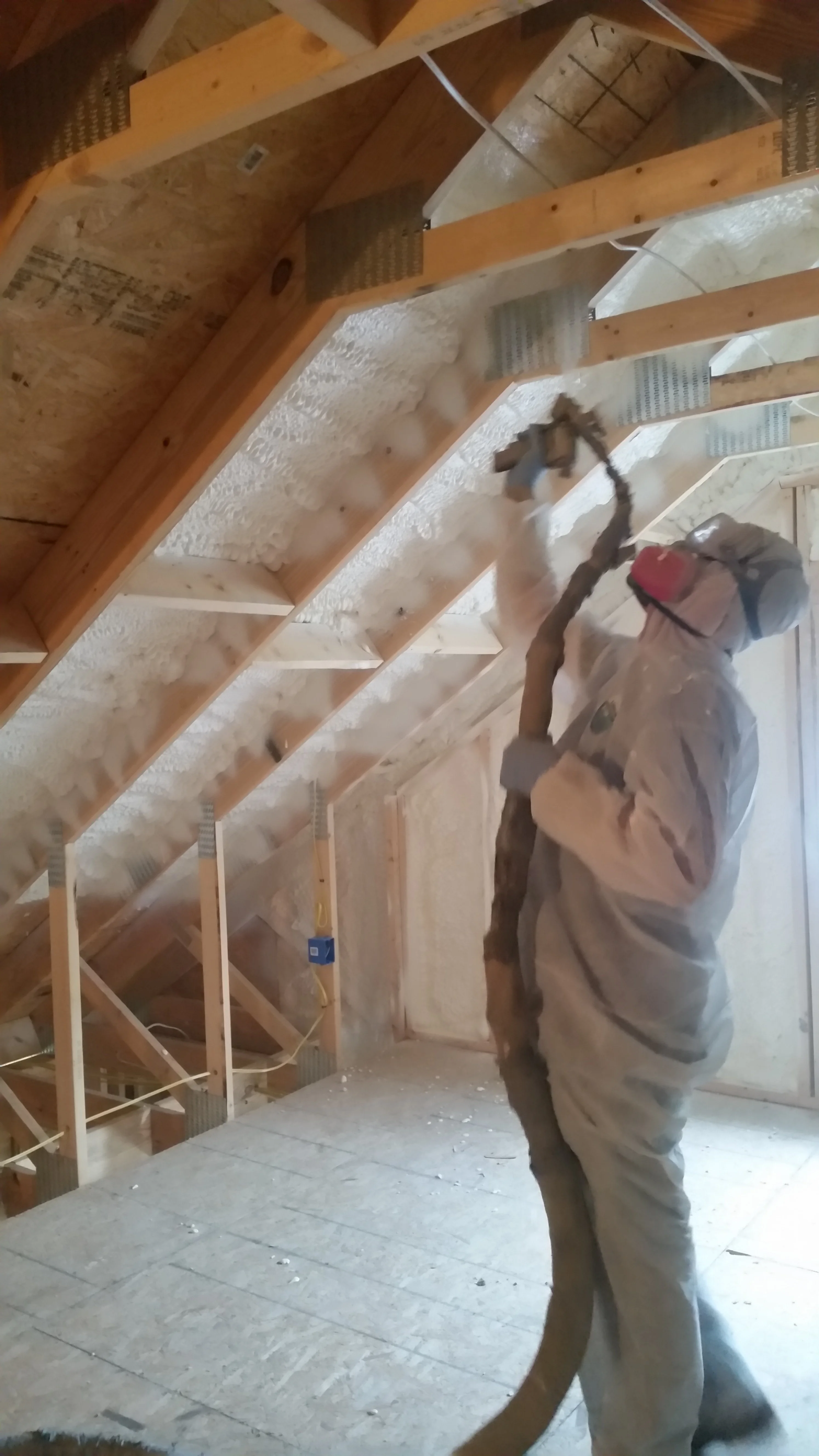 Worker spraying foam in attic space