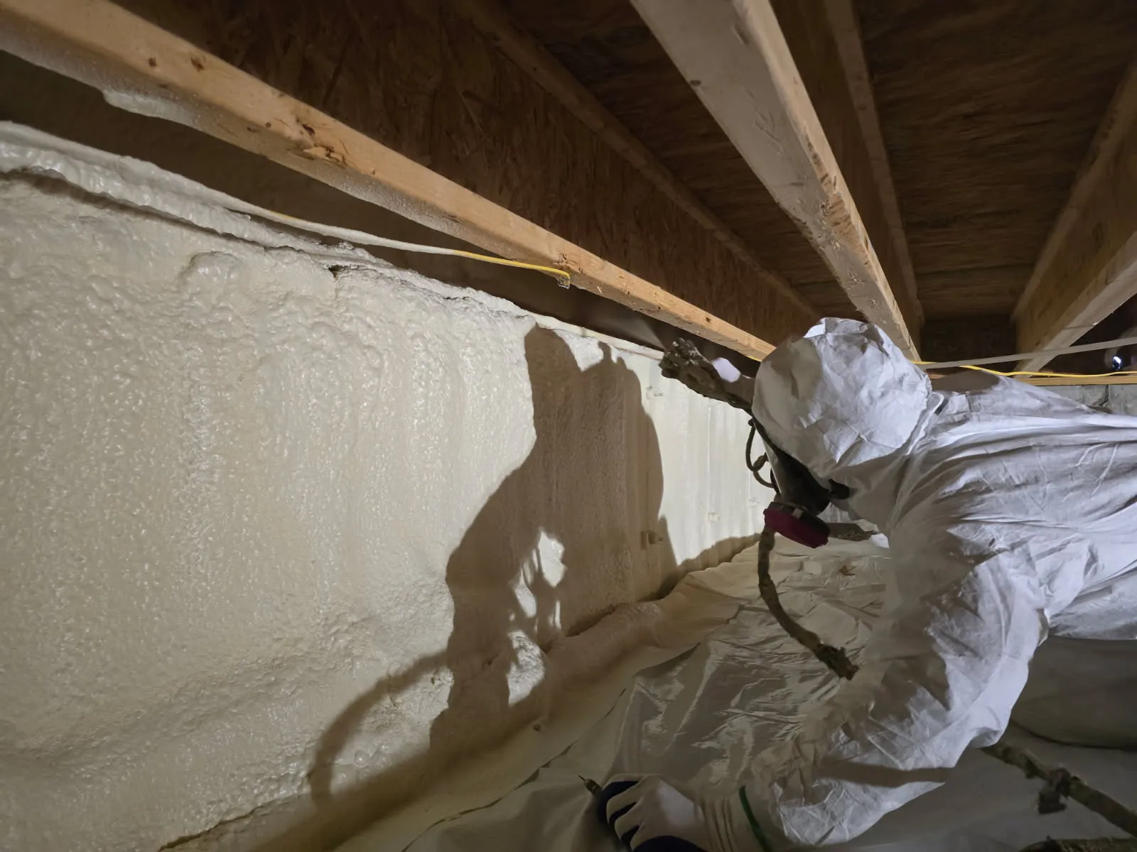 Worker spraying crawlspace foundation wall